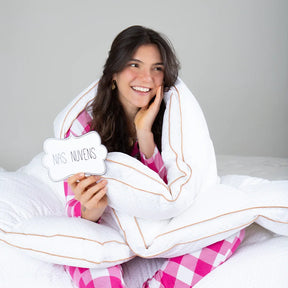 Mulher sorrindo sendo envolvida como em um abraço pelo nosso pillow top magnum demonstrando conforto premium e com uma plaquinha escrito que estar no pillow top magnum iws é como se sentir nas nuvens