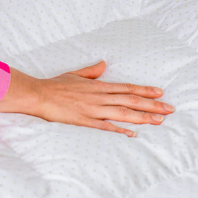 Mão feminina tocando no Pillow Top Magnum da i wanna sleep destacando seu conforto com a fibra AirFiber de alta qualidade e tecido 100% algodão, o Pillow Top Magnum AirFiber oferece uma maciez e suavidade excepcionais.