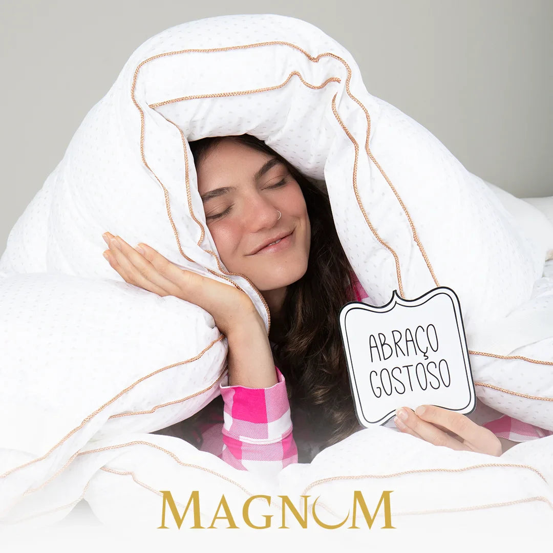 Mulher relaxando em sua cama envolvida pelo nosso pillow top magnum Pluma AirFiber IWS demonstrando seu conforto e maciez que lembra um abraço gostoso, sua  tecnologia de preenchimento gomo a gomo assegura um ajuste perfeito, independentemente do seu tipo de colchão proporcionando uma noite de sono digna de um hotel 5 estrelas.