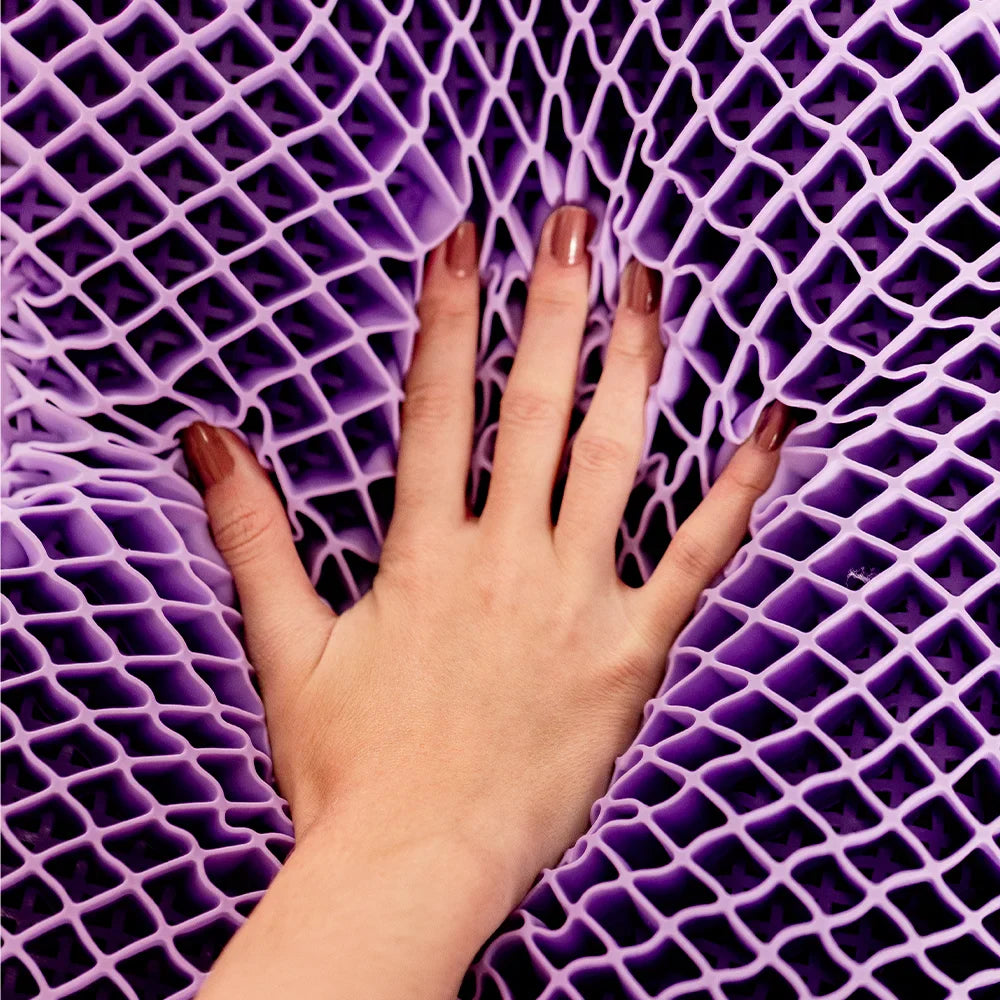 Nãos femininas com unhas pintadas em tom nude tocando em sua exclusiva estrutura construtiva do airgelly®  na cor roxa que garante uma distribuição uniforme da pressão da cabeça e pescoço, ajudando a aliviar e prevenir dores causadas por pontos de tensão.