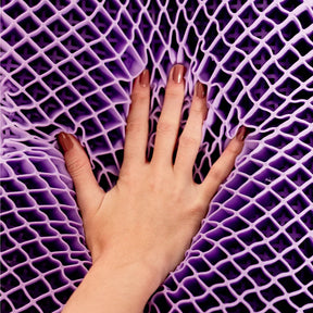 Nãos femininas com unhas pintadas em tom nude tocando em sua exclusiva estrutura construtiva do airgelly®  na cor roxa que garante uma distribuição uniforme da pressão da cabeça e pescoço, ajudando a aliviar e prevenir dores causadas por pontos de tensão.